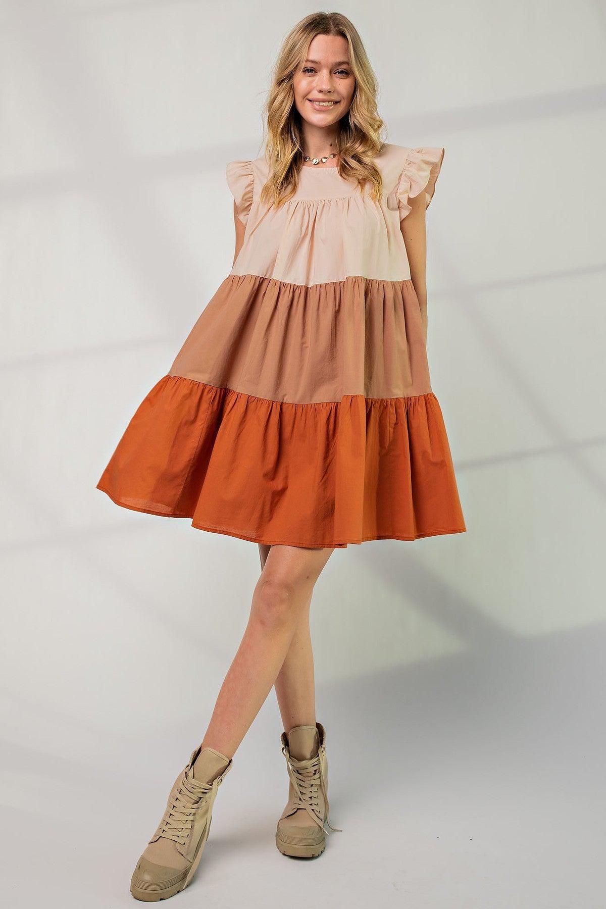 Woman wearing a poplin tiered color block dress with boat neckline and ruffle sleeves, featuring autumn hues and a loose fit.