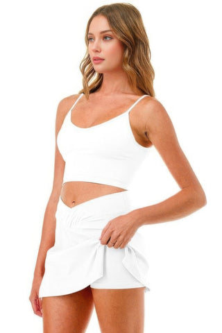 Woman wearing a white premium tennis pickleball short skirt skort with cross waistband and cellphone pocket.