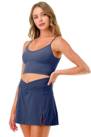 Woman wearing a blue premium tennis pickleball skort with cross waistband and mini skirt overlay, ideal for active sports like tennis or golf.