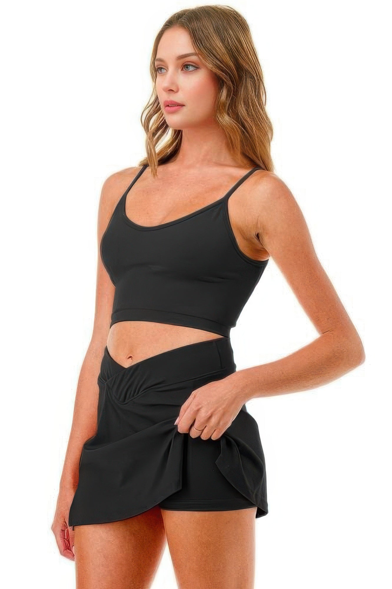 Woman wearing Premium Tennis Pickleball Short Skirt Skort with cross waistband, showing cellphone pocket, black activewear set.