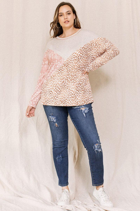 Plus size model wearing print block French terry top with boat neckline and 3/4 dolman sleeves, paired with distressed jeans.