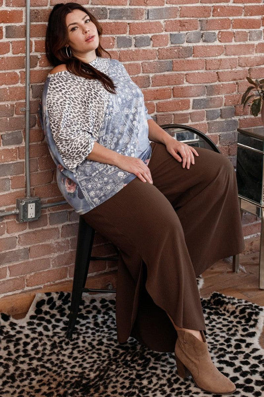 Woman wearing a print block French terry top with boat neckline and 3/4 dolman sleeves, paired with brown wide-leg pants.