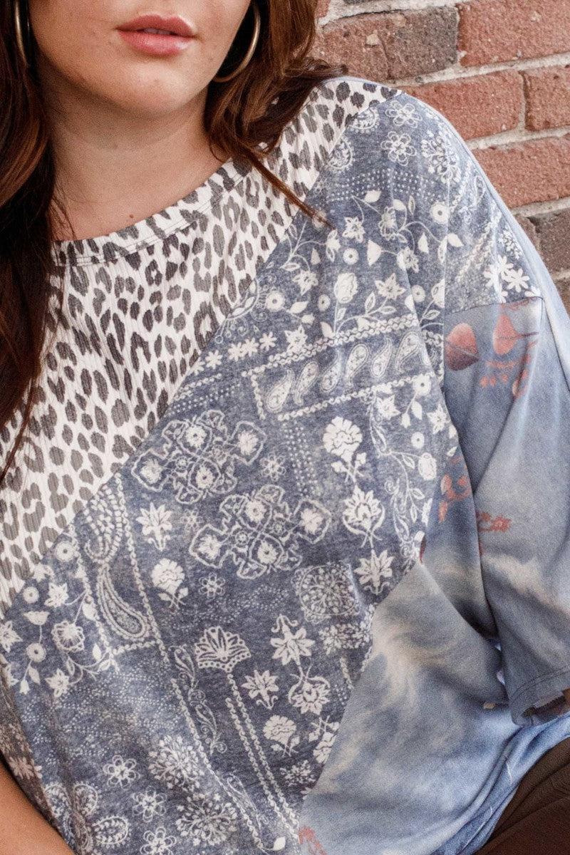 Plus size print block French terry top with boat neckline and dolman sleeves, featuring a denim print and leopard accents.