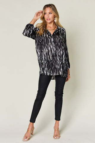 Woman wearing printed button-up long sleeve shirt made of 100% polyester with no stretch, featuring a frill design.