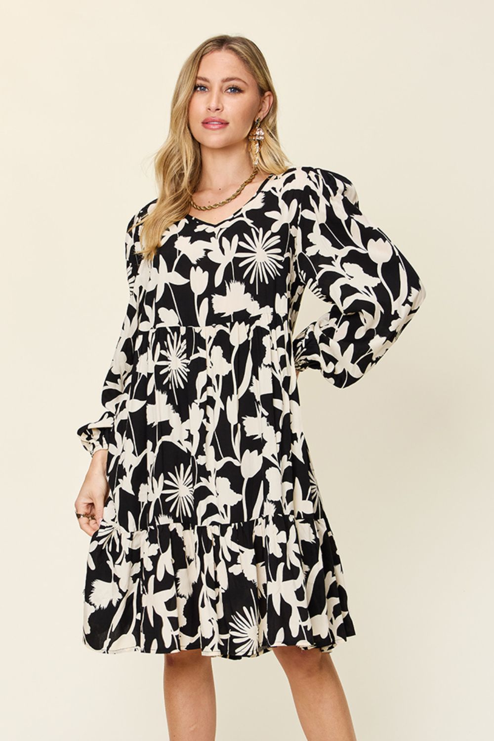 Black and white printed ruffle hem dress with pocket detail, featuring long sleeves and floral design. Made from 100% rayon.