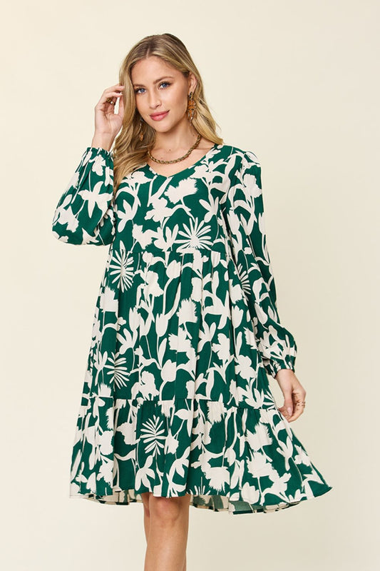 Woman wearing printed ruffle hem dress with pocket, featuring floral design and long sleeves, made of 100% rayon.