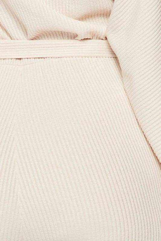 Cream ribbed fabric detail of an off shoulder waist tie long sleeve jumpsuit made from 90% polyester and 10% spandex.