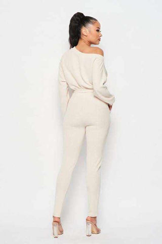 Cream off-shoulder jumpsuit with waist tie and long sleeves, made from 90% polyester and 10% spandex, shown from the back.
