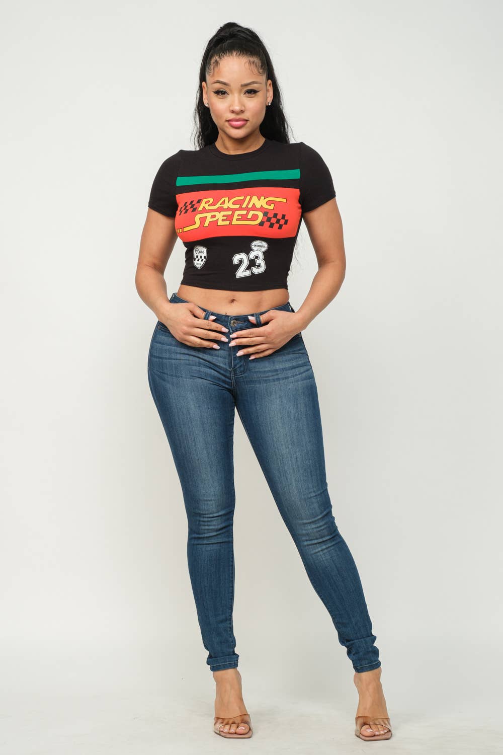 Woman wearing black Racing Speed front print crop top with jeans, standing confidently against a plain background.