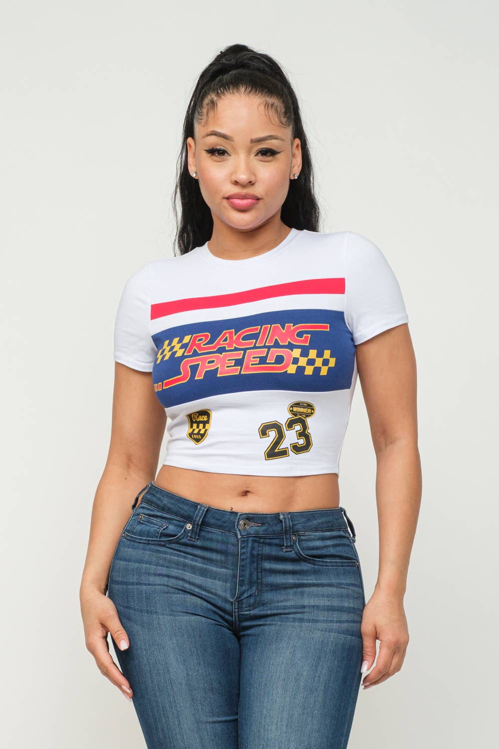 Woman wearing a white Racing Speed crop top with screen print design and blue jeans, showcasing casual fashion style.