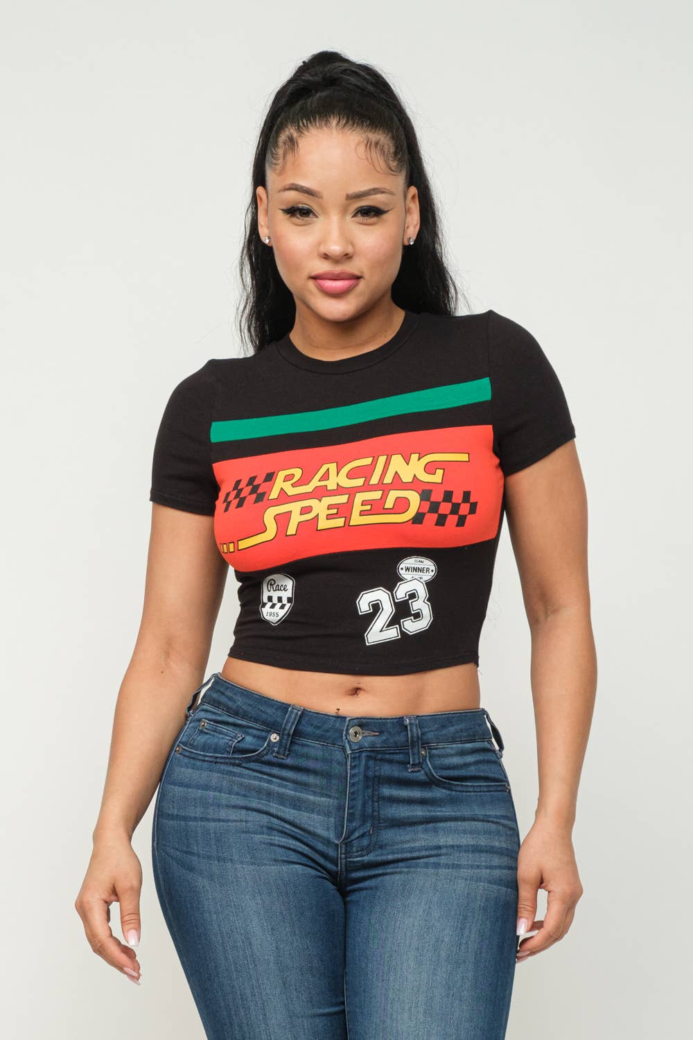 Woman wearing black Racing Speed crop top with vibrant screen print, round neck, short sleeves, and paired with jeans.