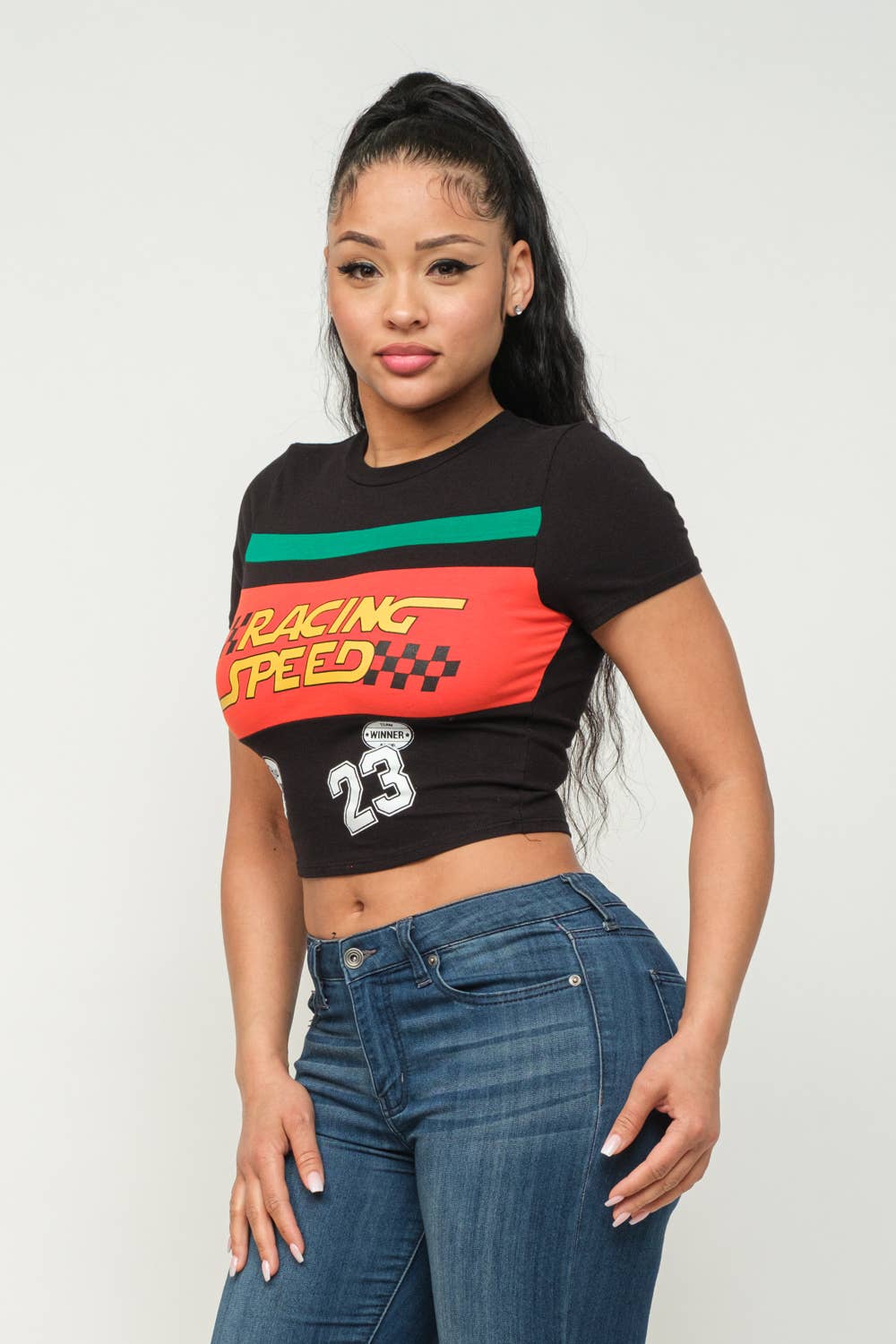 Woman wearing a black crop top with "Racing Speed" print, short sleeves, and jeans.