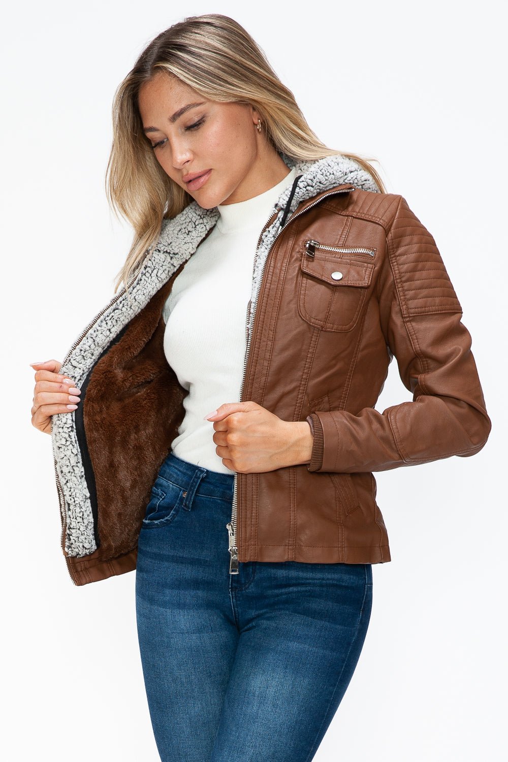 Woman wearing removable faux layered multi-pocket brown jacket with fuzzy hood and white tee.