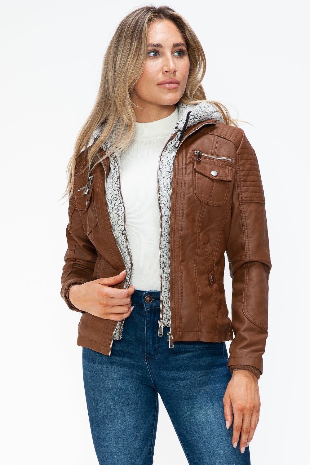 Woman wearing a removable faux layered multi-pocket jacket with a fuzzy hood, showcasing its stylish design and brown pleather material.