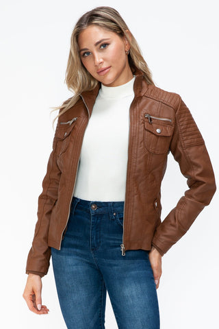 Woman wearing brown removable faux layered multi-pocket jacket with fuzzy hood and pleather material.