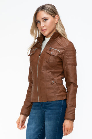 Woman wearing brown faux leather jacket with multiple pockets and stand collar.