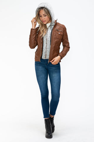 Model wearing a brown pleather jacket with removable faux layered design, multi-pockets, and a fuzzy hood.