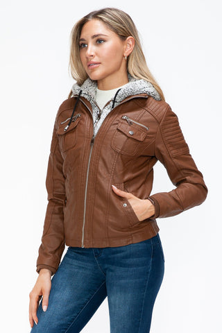 Woman wearing a brown removable faux layered jacket with multiple pockets and a fuzzy hood.