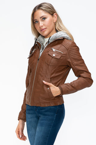 Woman wearing a brown removable faux layered jacket with fuzzy hood, featuring multiple pockets and pleather material.