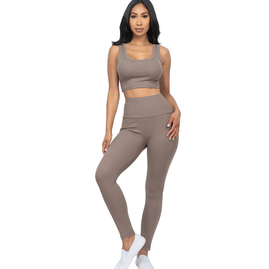 Woman wearing a ribbed crop top and leggings set in taupe color, featuring a comfortable and stylish fit made of 92% polyester and 8% spandex.