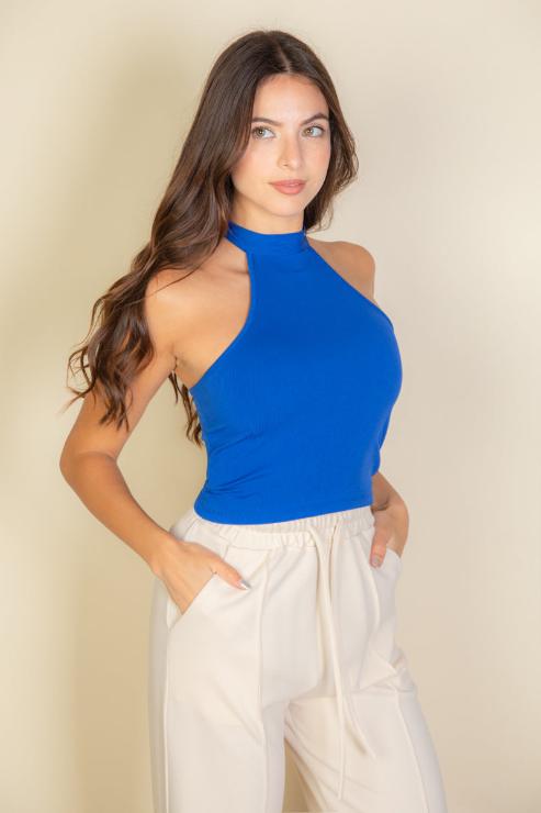 Model wearing a blue ribbed halter neck backless top paired with white pants, showcasing a soft, stretchy fabric blend of polyester and spandex.