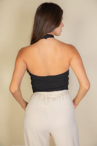 Woman wearing black ribbed halter neck backless top with light pants, showcasing back view and fabric texture