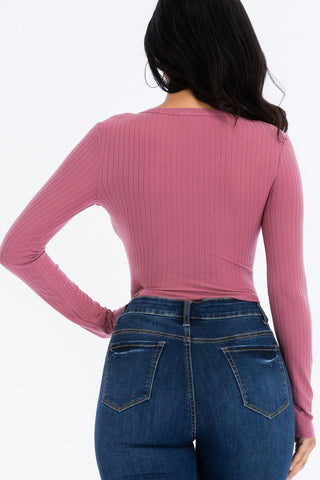 Back view of ribbed long sleeve snap button down crop top in pink with high stretch fabric, paired with blue denim jeans.