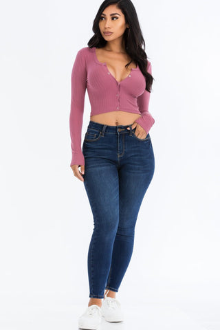 Model wearing a ribbed long sleeve snap button down crop top in pink with jeans, showcasing soft, high stretch fabric. Fashion outfit.