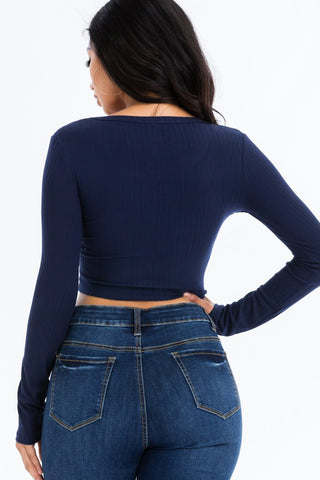 Back view of model wearing ribbed long sleeve snap button down crop top with blue jeans