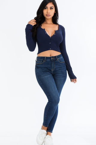 Woman wearing navy blue ribbed long sleeve snap button crop top with jeans, showcasing casual chic fashion style.