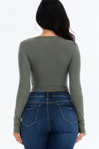 Back view of a woman wearing a ribbed long sleeve green crop top styled with high-waisted jeans, highlighting textures and fit.