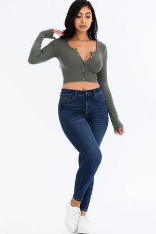 Woman wearing ribbed long sleeve snap button down crop top with jeans, showcasing stylish casual outfit.