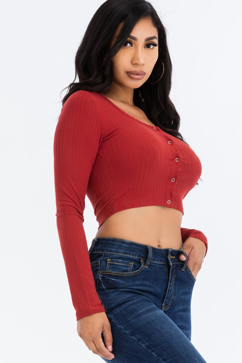 Woman wearing a ribbed red long sleeve snap button down crop top with high stretch, paired with blue jeans.