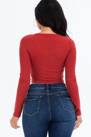 Back view of a woman wearing a red ribbed long sleeve snap button down crop top with jeans.