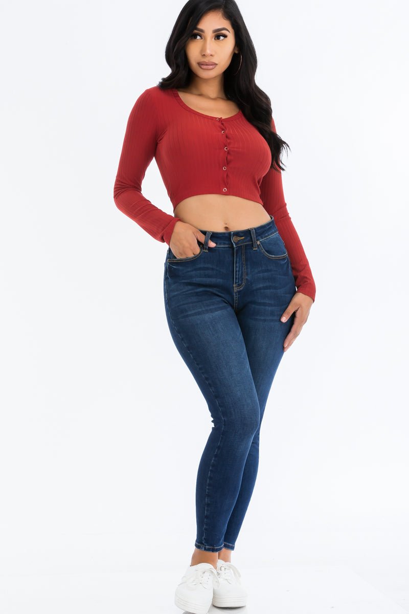 Model wearing a ribbed long sleeve snap button down crop top in red, paired with blue jeans.