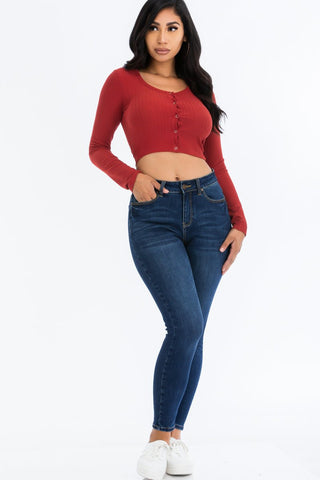 Model wearing a ribbed long sleeve snap button down crop top in red, paired with blue jeans.