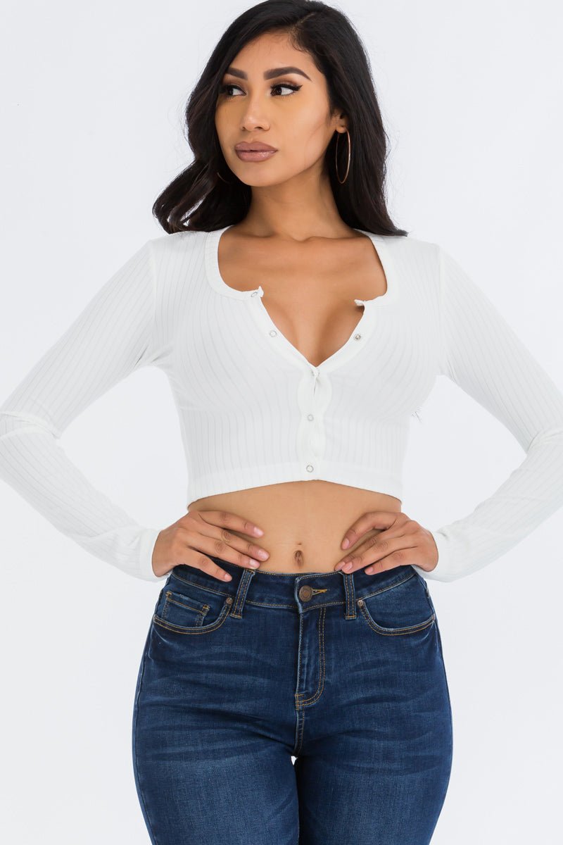 Model wearing a white ribbed long sleeve snap button down crop top made of soft high stretch rib knit fabric, paired with blue jeans.