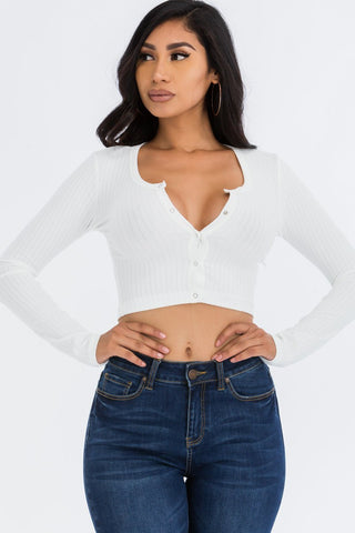 Model wearing a white ribbed long sleeve snap button down crop top made of soft high stretch rib knit fabric, paired with blue jeans.