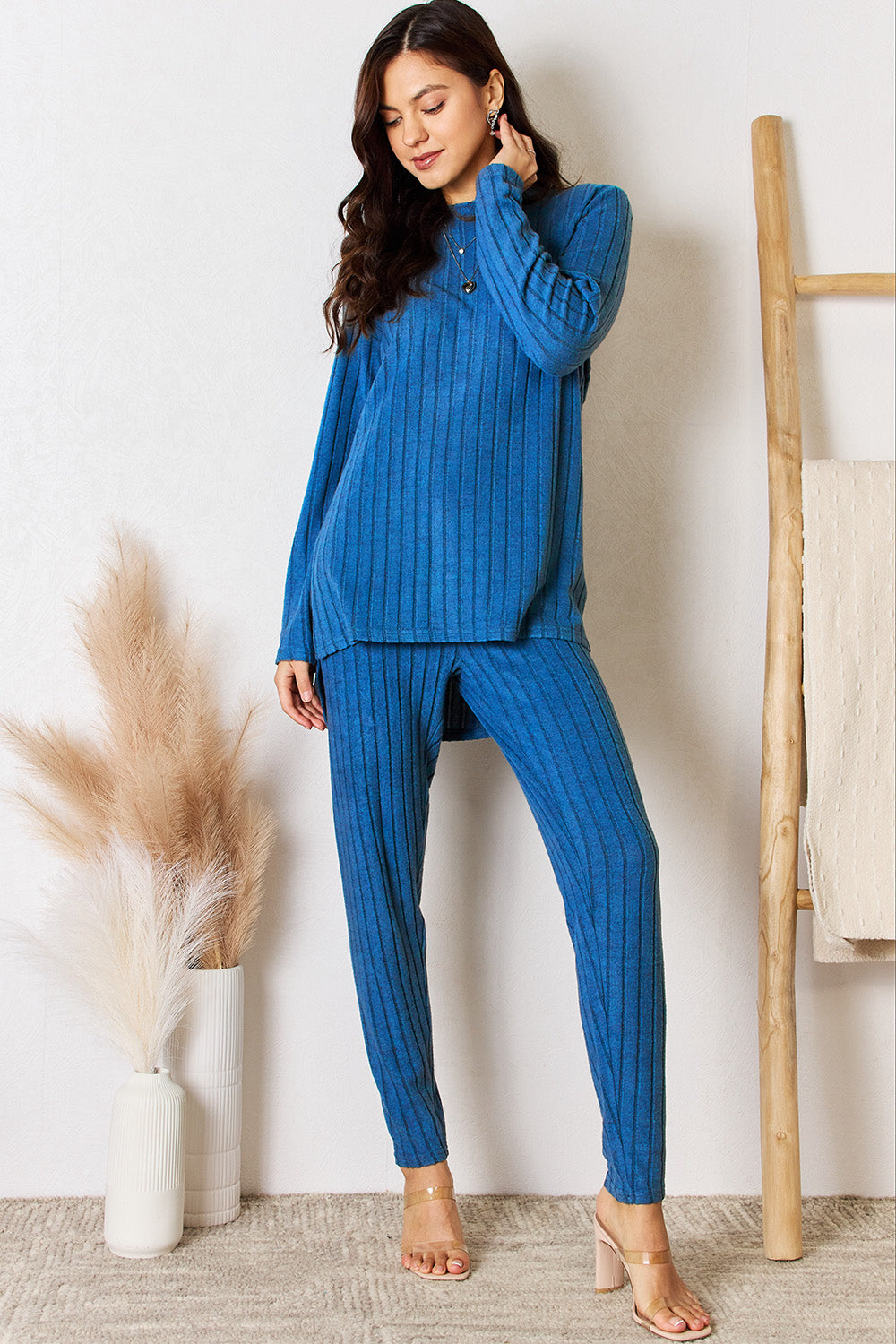 Woman wearing a blue ribbed round neck high-low slit top and pants set, made from slightly stretchy polyester and elastane blend.