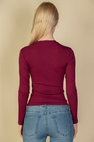 Back view of a model wearing a burgundy ribbed round neck long sleeve top paired with blue jeans.
