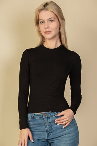 Model wearing black ribbed round neck long sleeve top, soft medium weight stretch rib knit, paired with denim jeans.