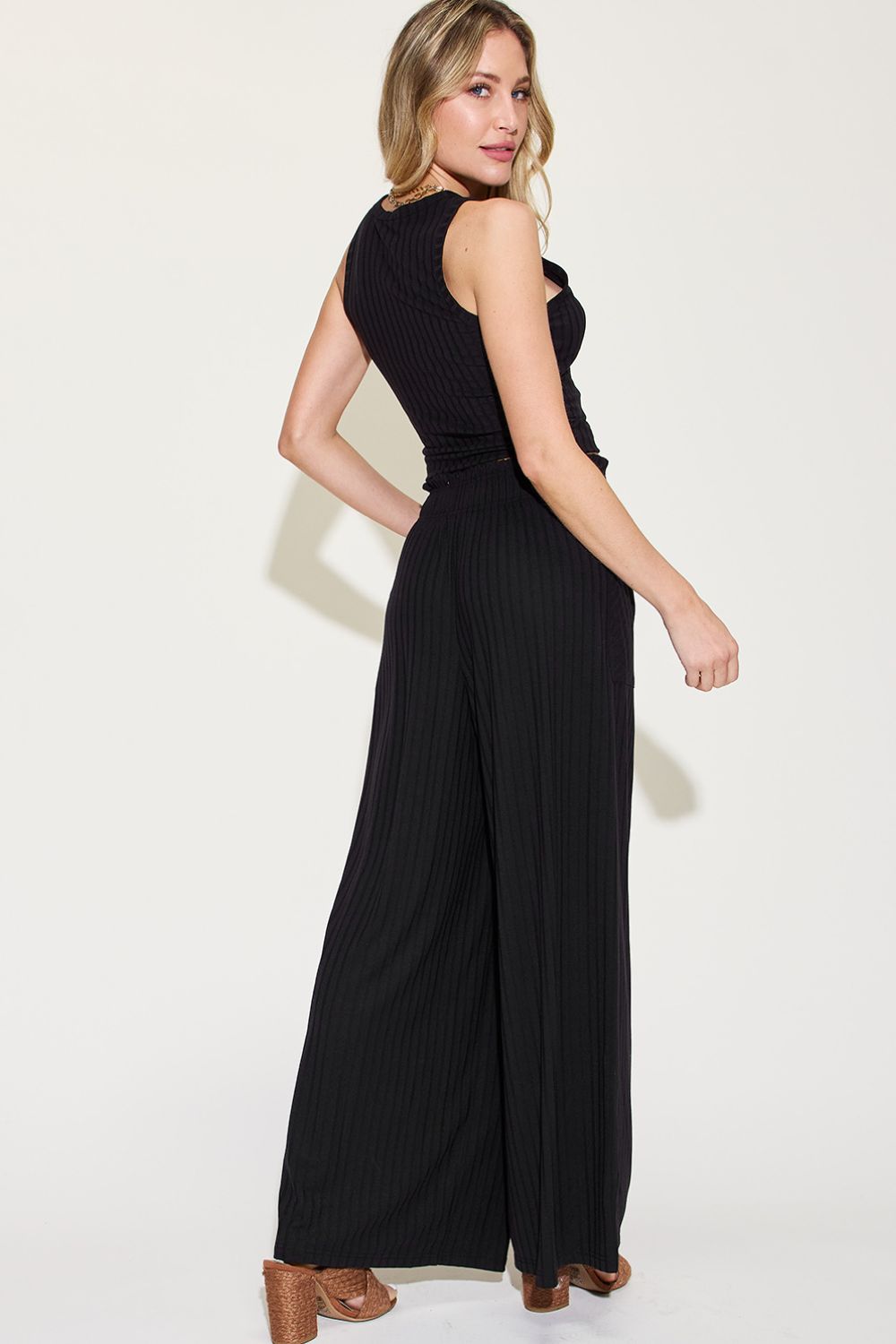 Woman wearing ribbed tank and wide leg pants set in black with pockets and frill details, made of polyester, rayon, and spandex.