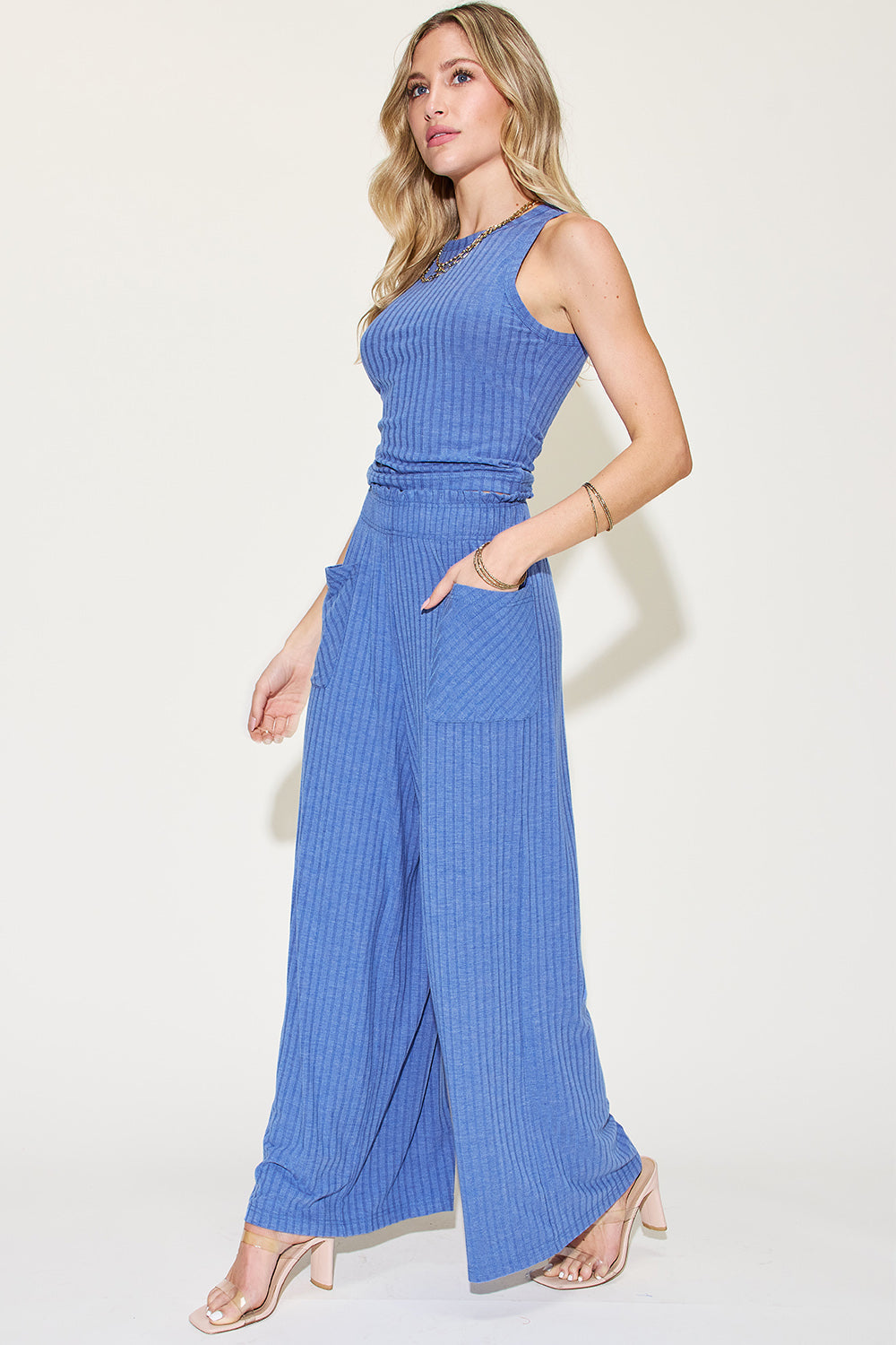 Woman wearing blue ribbed tank and wide leg pants set with pockets and frill, made of polyester, rayon, and spandex.