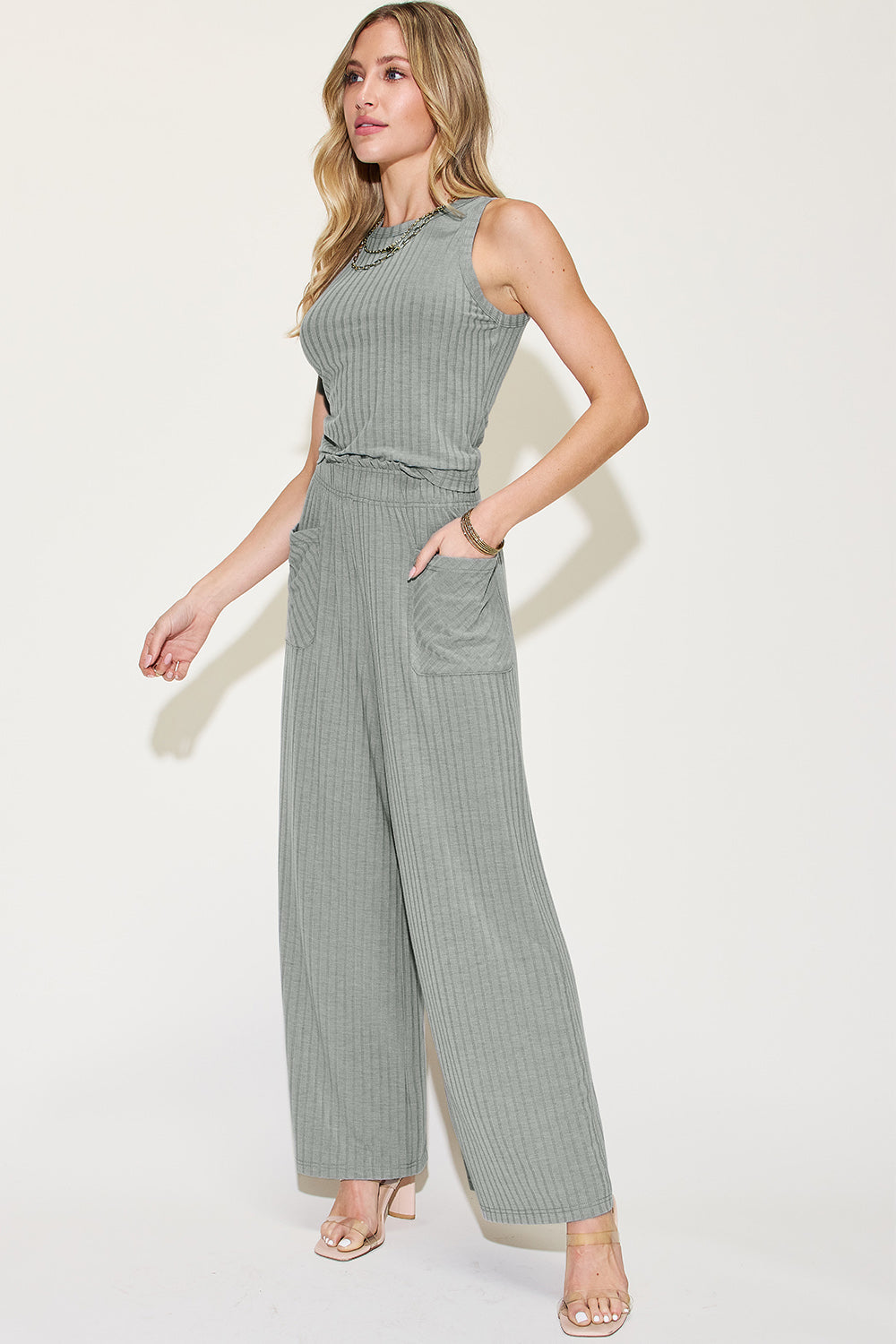 Woman modeling a ribbed tank and wide-leg pants set in green with frill detailing and pockets, made from polyester, rayon, and spandex mix.