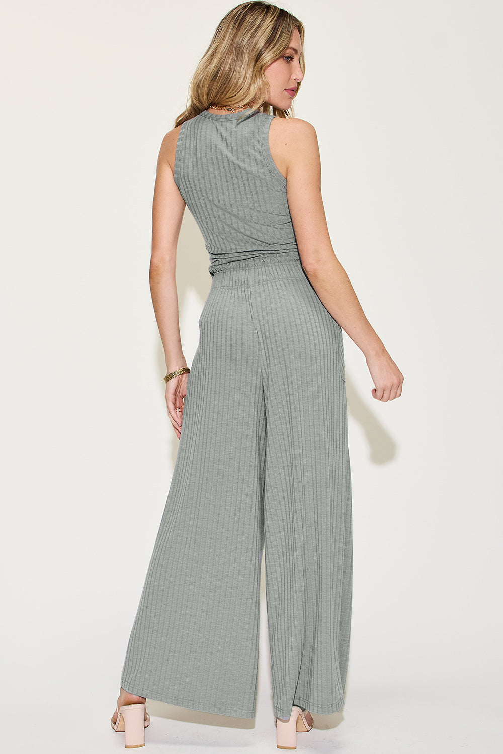 Woman wearing ribbed tank and wide leg pants set, featuring a frill design and pocket, made of polyester, rayon, and spandex.