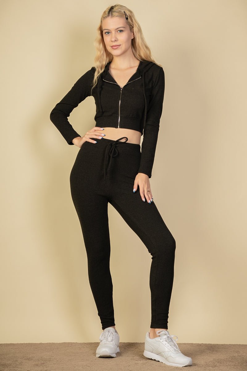 Model wearing black ribbed tie front leggings with elastic drawstring, crafted in two-tone brushed rib knit fabric, paired with white sneakers.