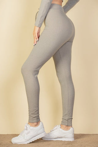 Side view of model wearing ribbed tie front leggings with elastic drawstring, showing fabric texture and fit, paired with white sneakers.