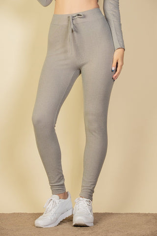 Ribbed tie front leggings in gray, featuring a soft elastic drawstring band, worn by model in stylish pose against a beige background.
