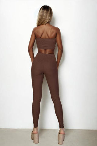 Back view of a woman wearing a ribbed tube top and leggings set in brown, showcasing a bodycon fit, made of polyester and spandex.