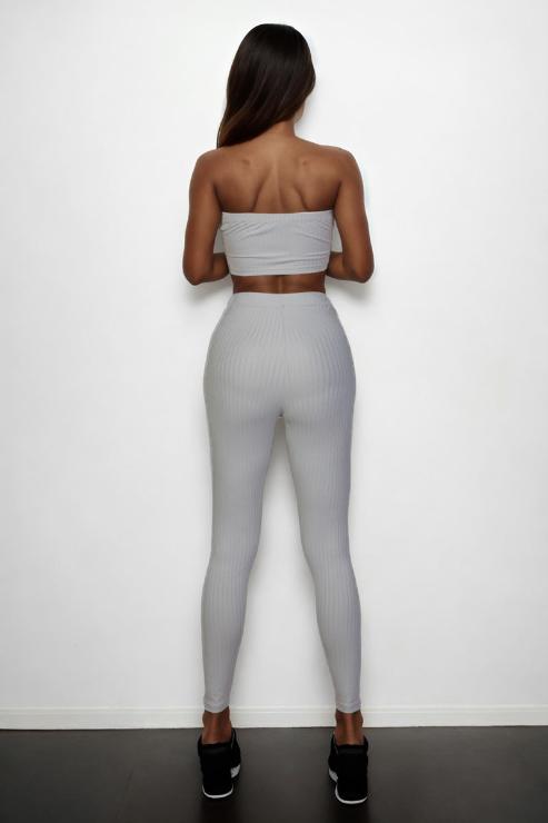 Back view of model wearing ribbed tube top and leggings set in gray, polyester and spandex blend, featuring a bodycon fit.